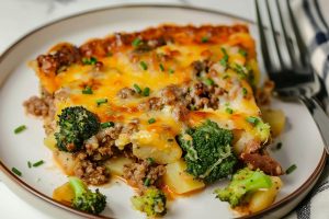 Super Close Up of Italian Sausage Breakfast Casserole Slice with Broccoli, Italian Sausage, Potatoes, and Cheese on a White Plate