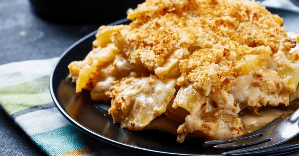 Serving of potato casserole on a black plate with fork.