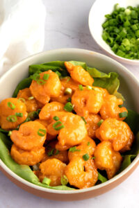 Bowl of Homemade Bang Bang Shrimp with Green Onions and Lettuce