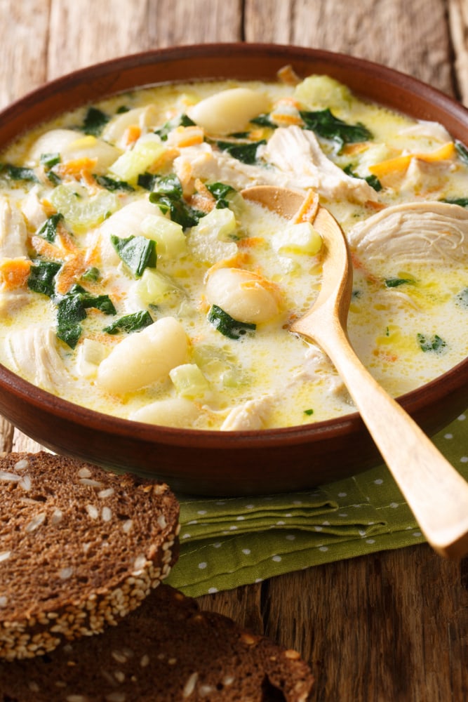 Chicken gnocchi soup served in a wooden bowl with wooden spoon. 