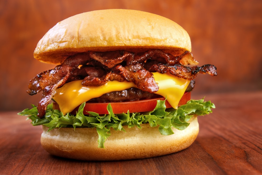 Burger with lettuce, bacon, cheese, and tomato