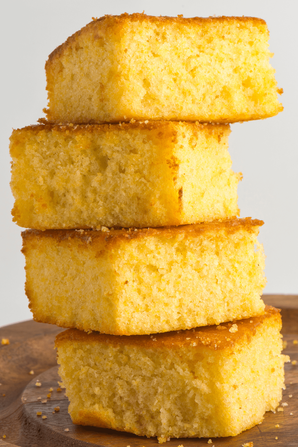 Stack of sliced cornbread bars on a wooden board.