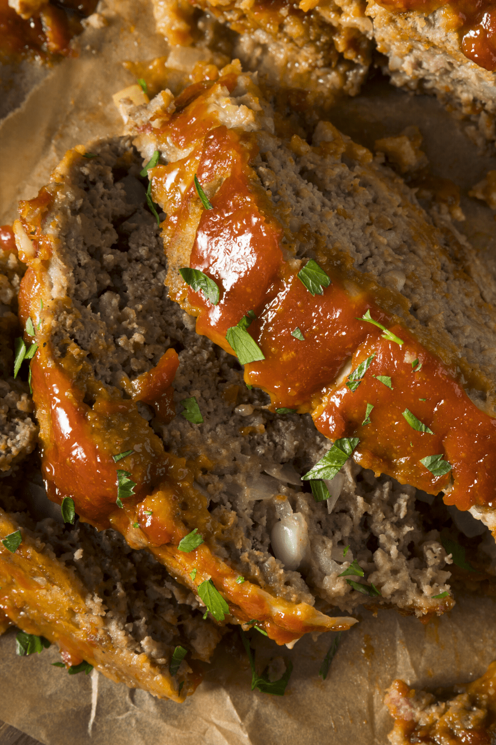 Sliced Meatloaf with ketchup on a parchment paper garnished with chopped parsley
