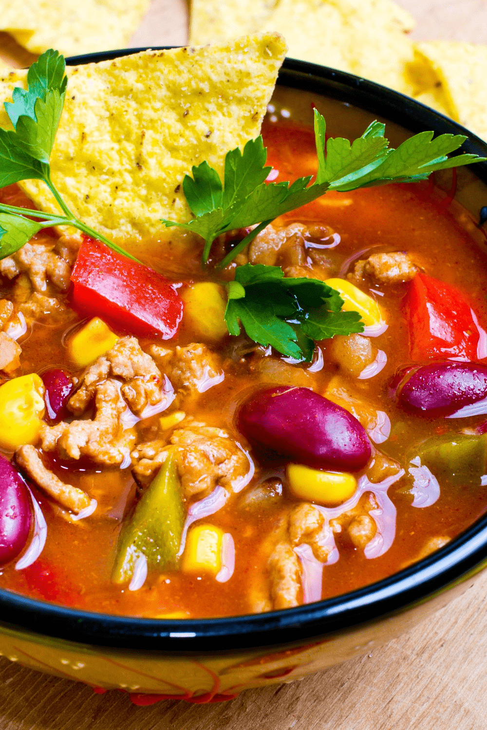 Closeup of taco soup loaded with beans, vegetables and ground meat served on a black bowl.