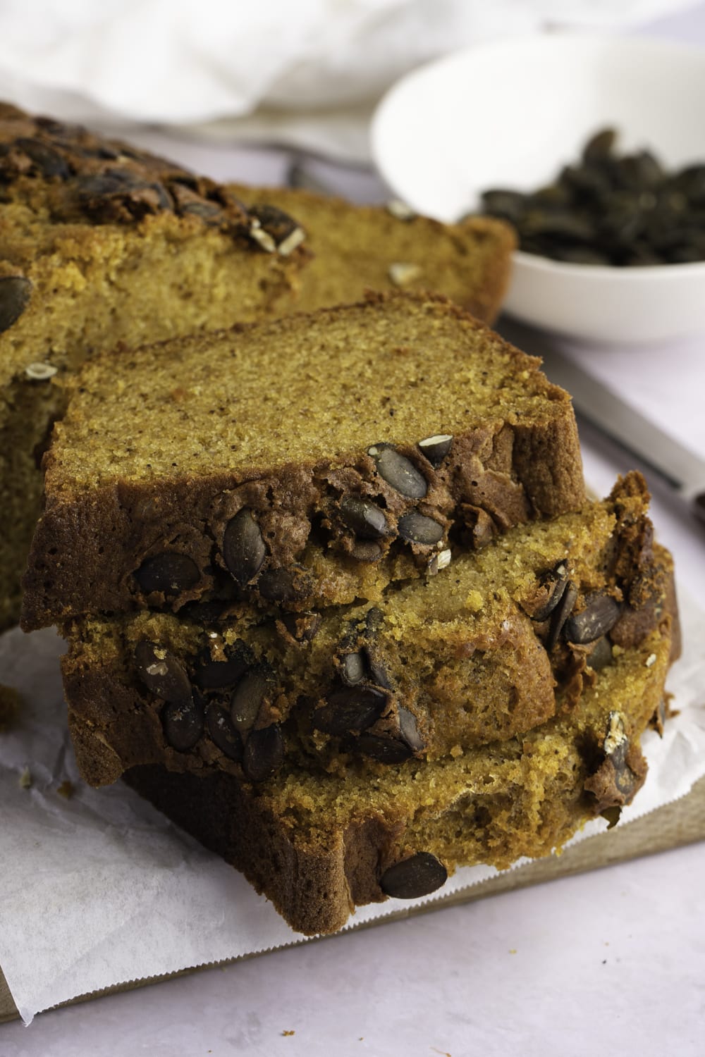 Sliced pumpkin loaf bread with pumpkin seeds on a wooden board. 