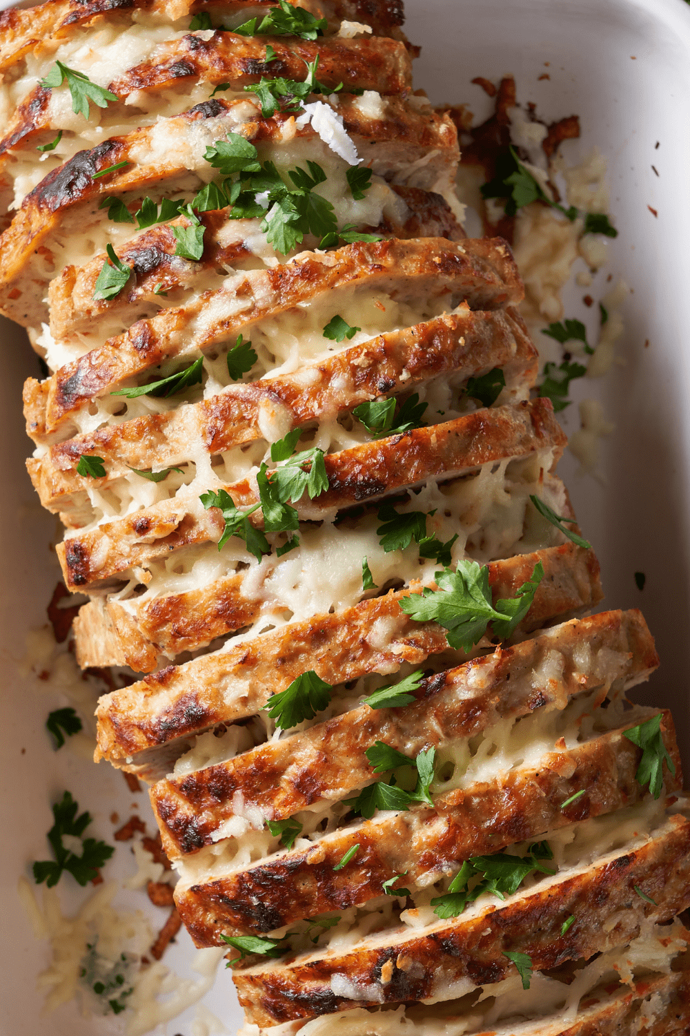 Sliced cheeseburger meatloaf with cheesy filling and garnished with chopped parsley.