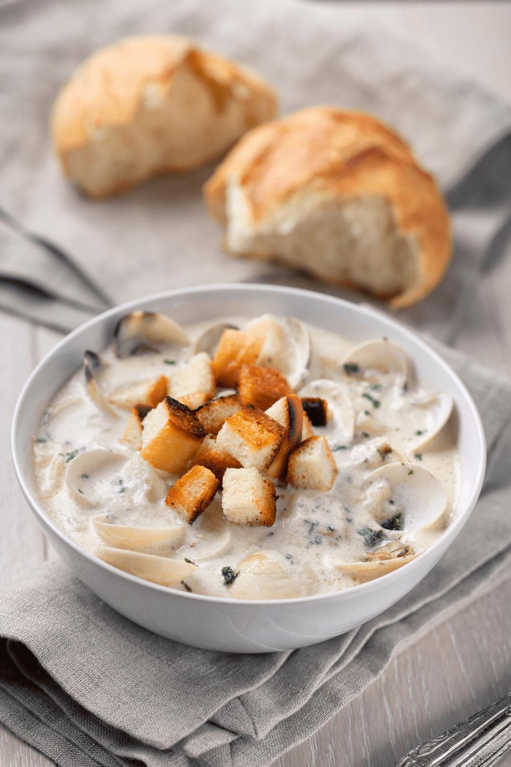 Bowl of Clam Chowder with bread crumbs on table with gray table cloth