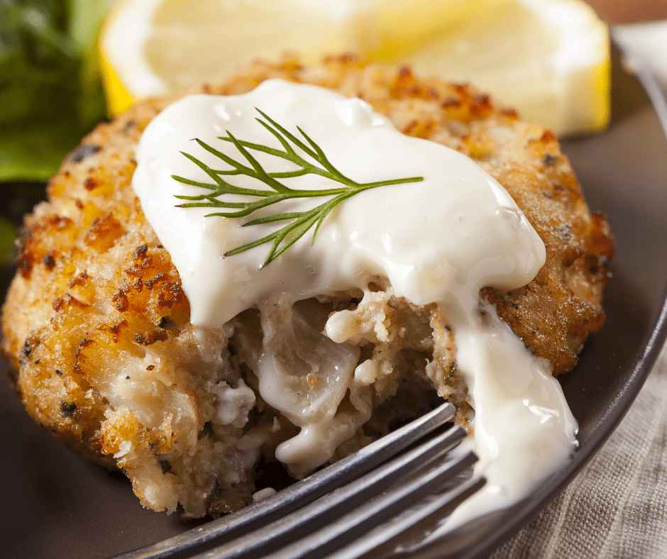 A serving of crab cake topped with white sauce.