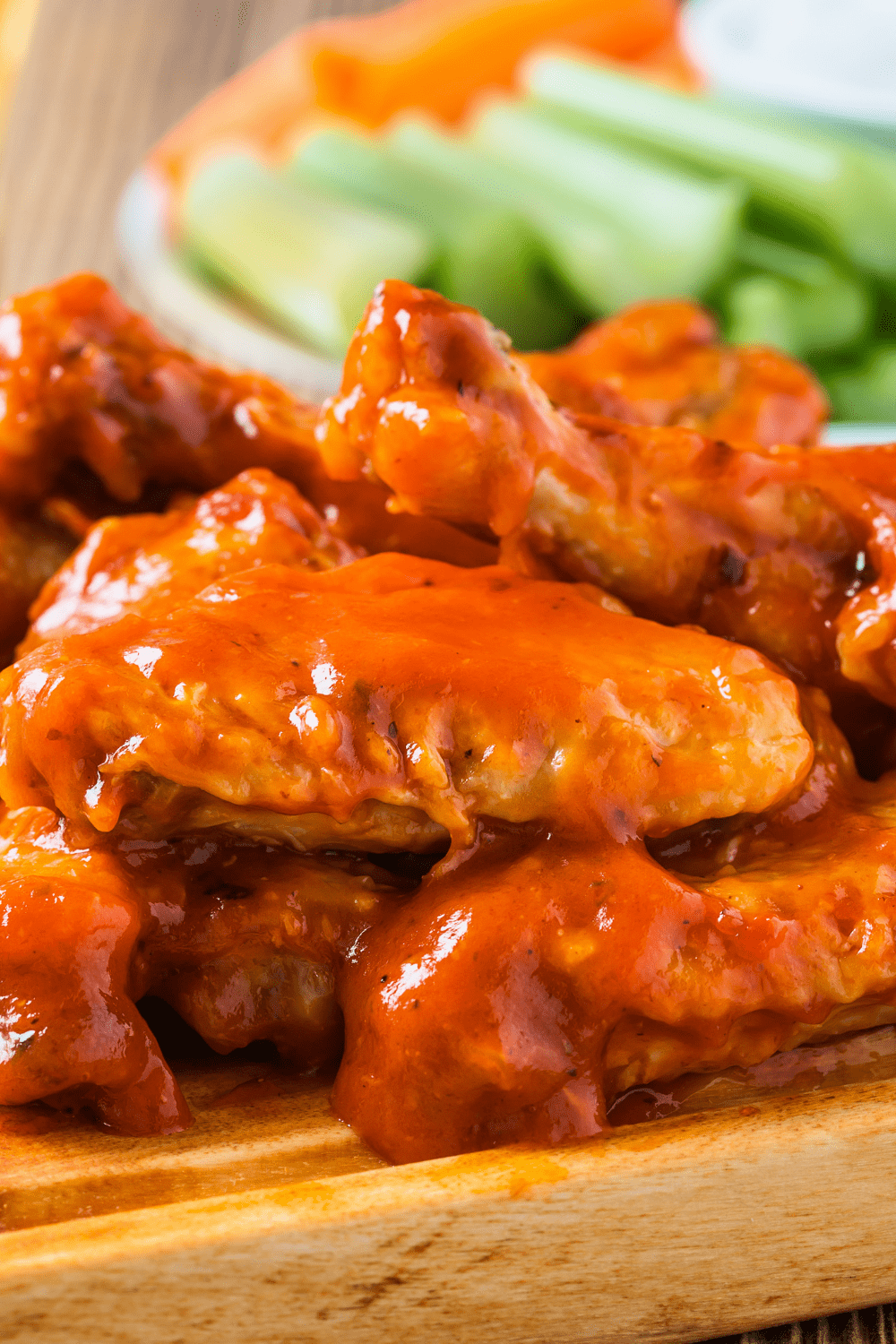 Chicken wings on a wooden board covered with buffalo sauce. 