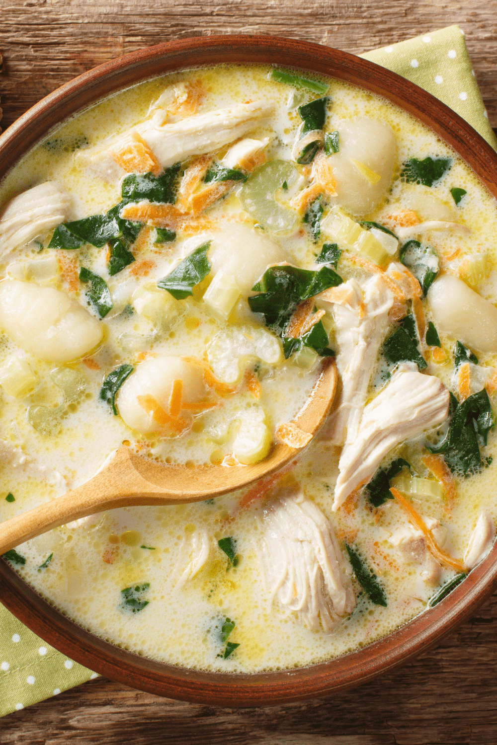 Creamy chicken gnocchi soup with a wooden spoon. 