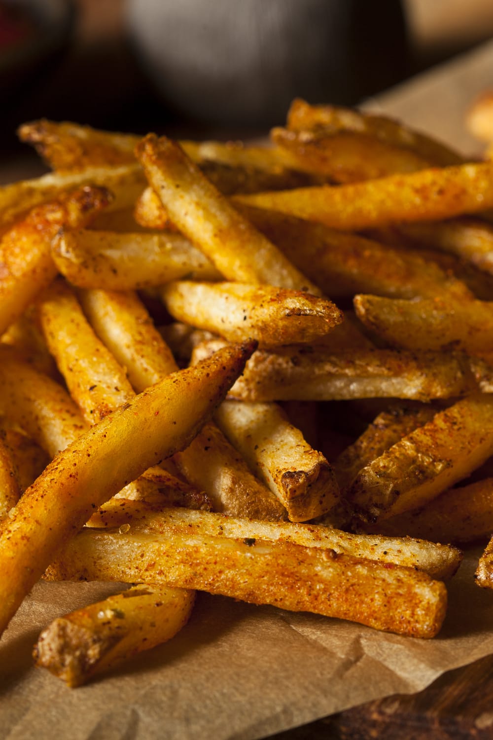 Bunch of Cajun Seasoned Fries on a brown parchment paper.