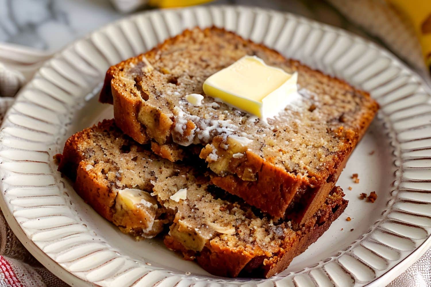 Super Close Up of Two Slices of Paula Deen Banana Bread with Butter on a White Plate