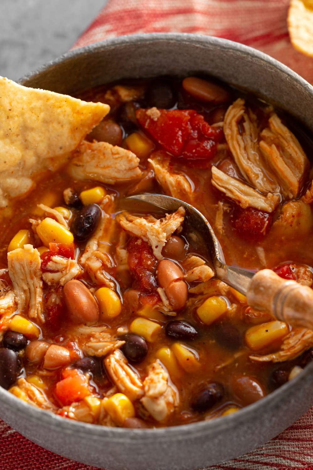 Soup with beans, tortilla and shredded chicken on a pot.