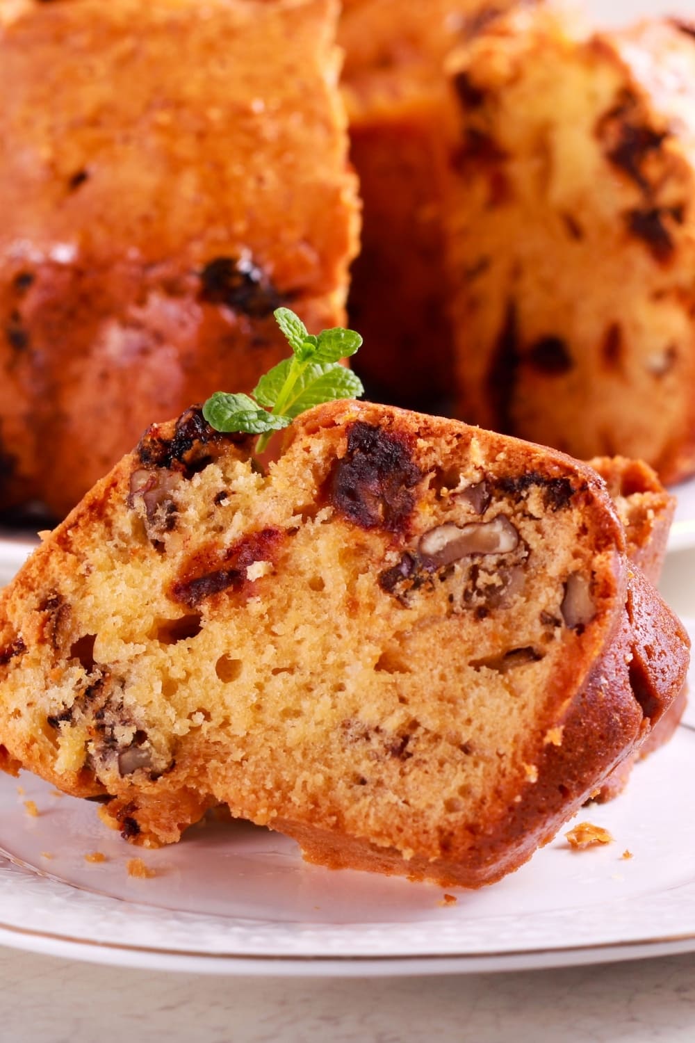 A slice of orange cake with chopped pecans.