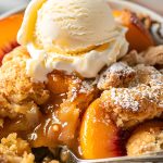 Cake Mix Cobbler with Peaches in a Serving Bowl with Vanilla Ice Cream and a Spoon