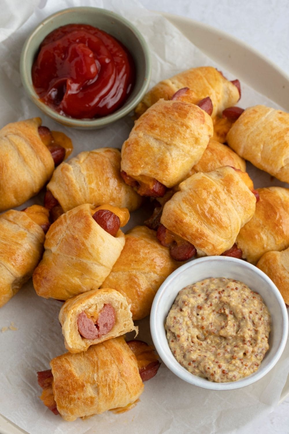 Bunch of pigs in a blanket with dipping sauces.