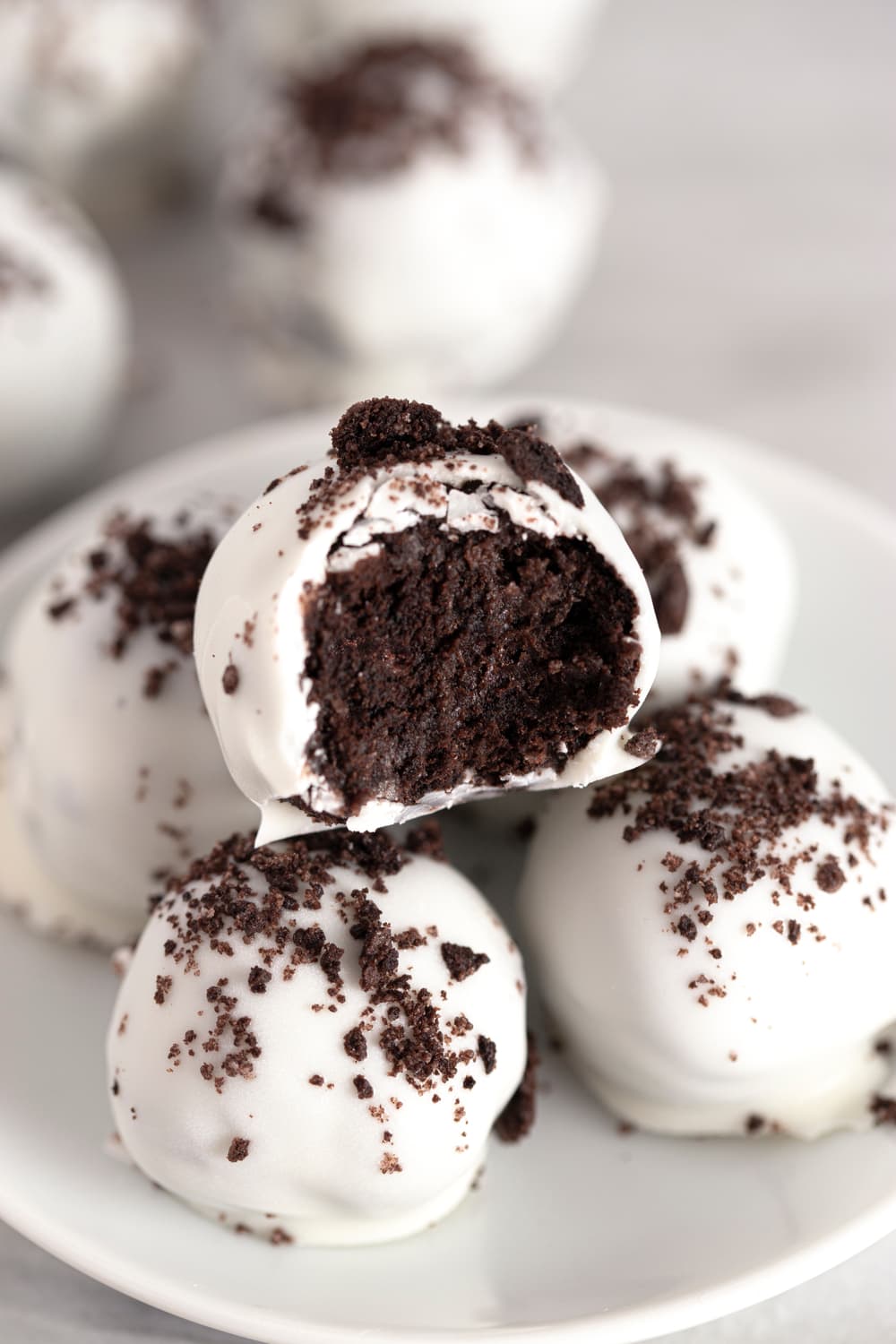 White chocolate covered  chocolate cake balls sprinkled with crushed Oreos. 