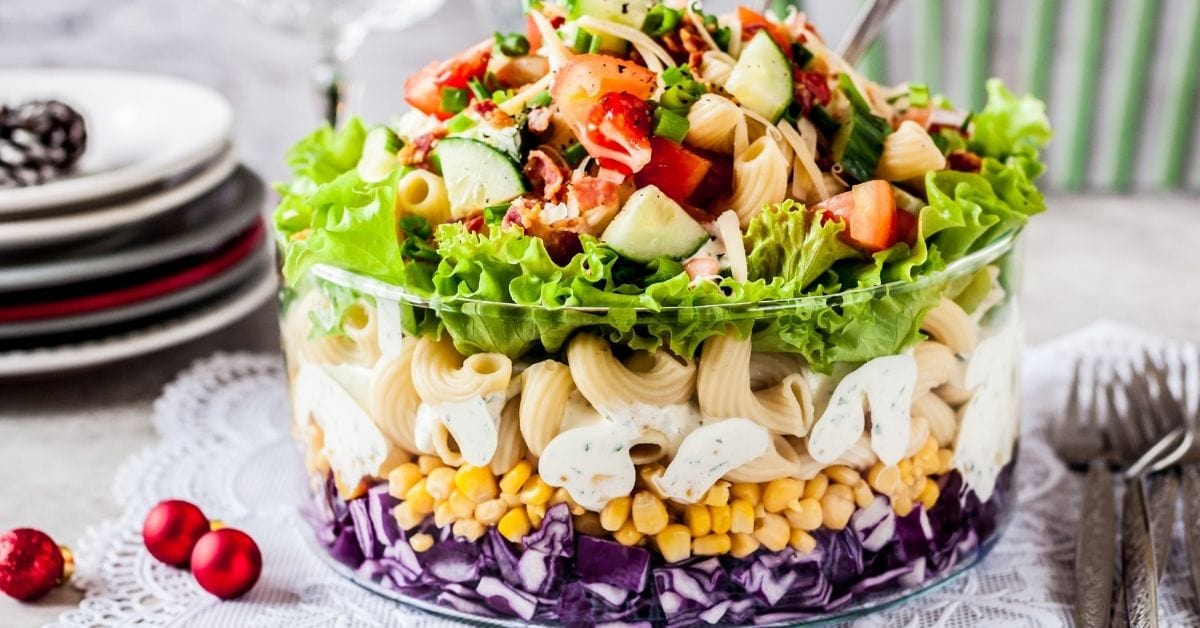 A Bowl of Layered Pasta Salad with Red Cabbage, Corn, Tomatoes, Cucumber and Herbs