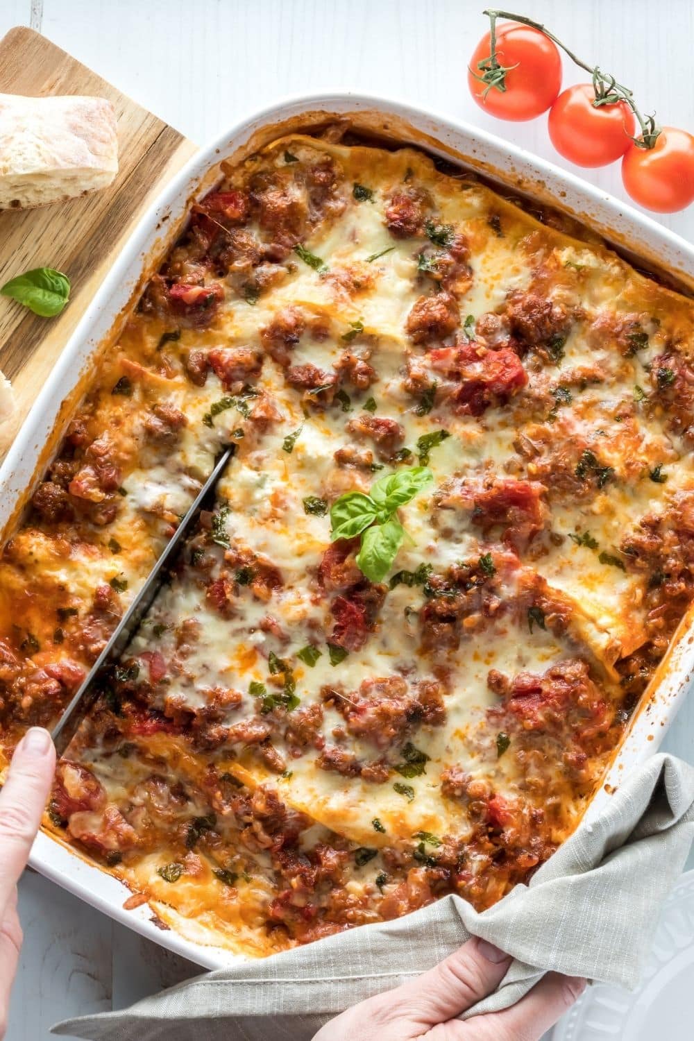 Cheesy, Meaty Ragu Lasagna in a Casserole Dish with Someone Cutting a Slice