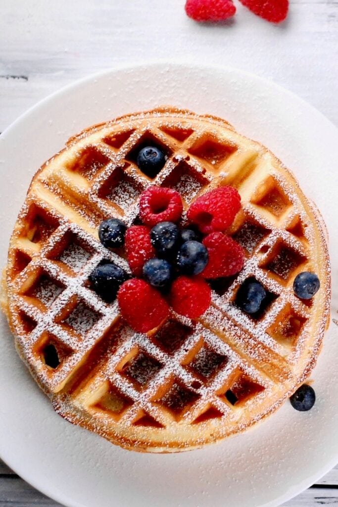 Homemade Buttermilk Waffles with Berries on a plate with powdered sugar