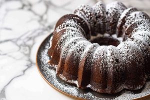 Too Much Chocolate Cake Bundt on a Serving Plate on a White Marble Table