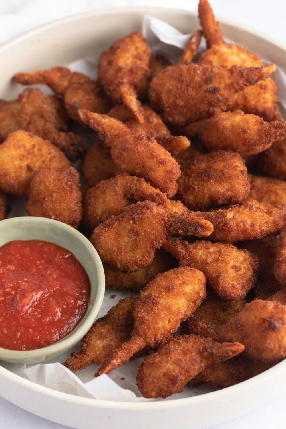 Air Fryer Breaded Frozen Shrimp with Red Cocktail Sauce on Parchment Paper in a Serving Dish