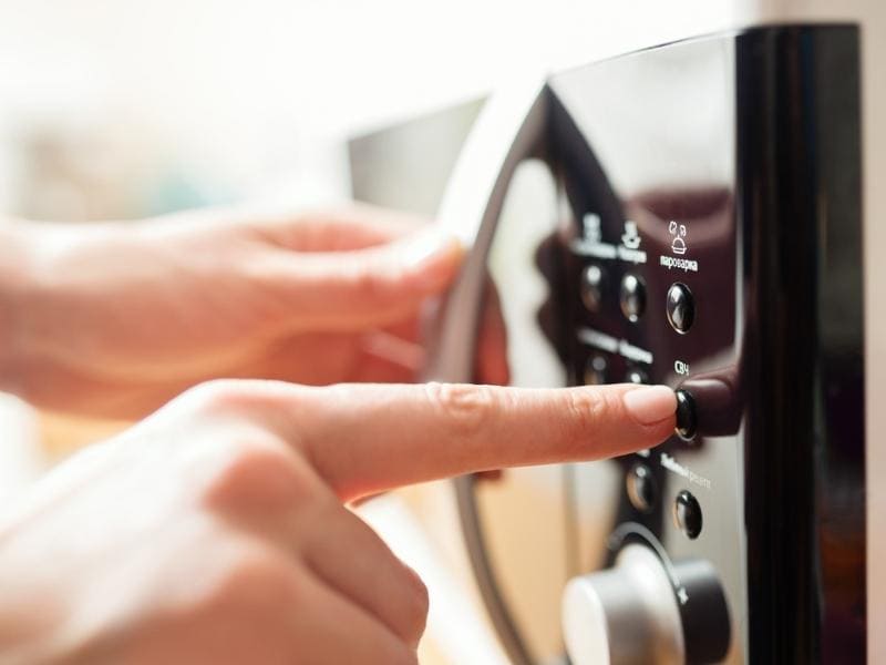 A Person Operating On A Microwave Oven