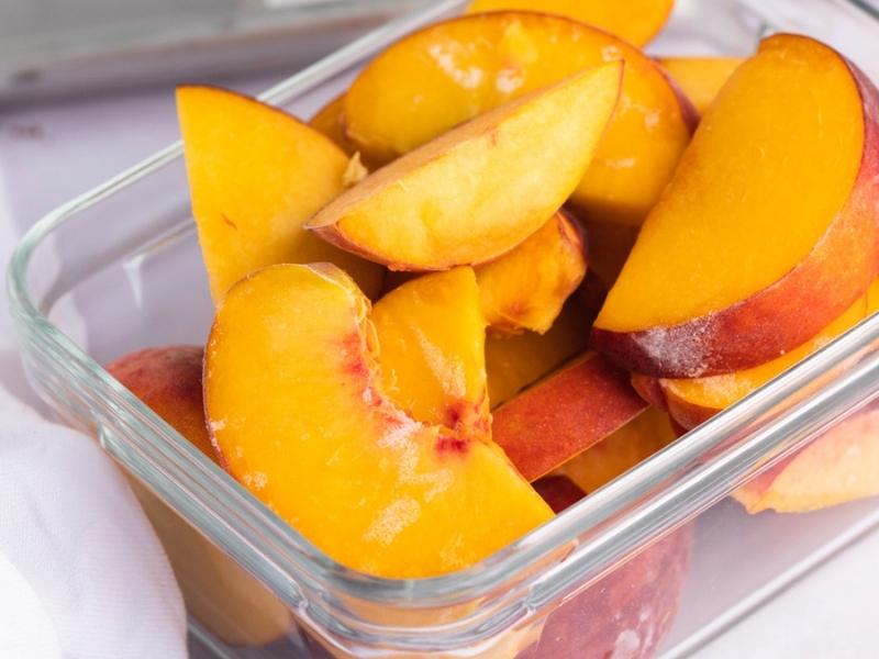 How to Freeze Peaches: frozen peaches in a clear square container