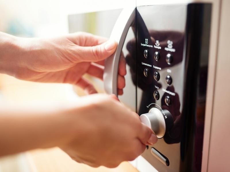 A Person Using A Microwave Oven