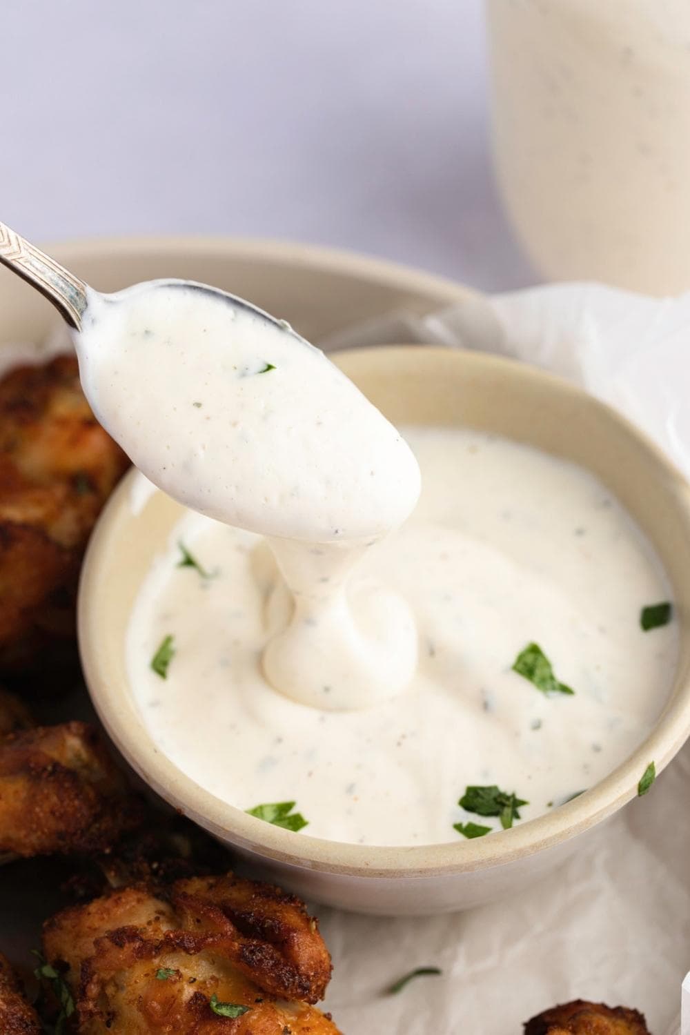 Bowl of ranch dressing with fried chicken wings on the side 
