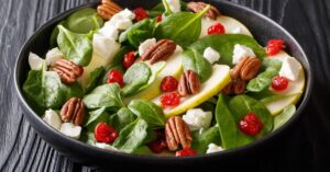 Homemade Healthy Pear Salad with Walnuts, Cherries and Cheese in a Black Plate