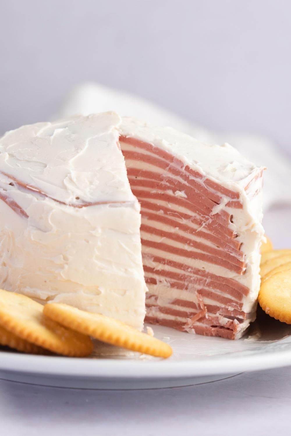 Sliced layered bologna covered with cream served with crackers.