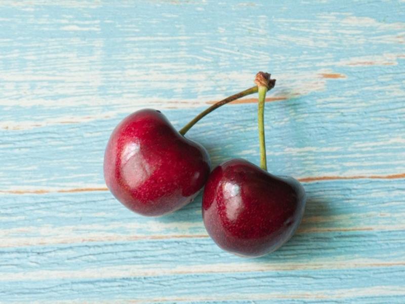 Two Bing Cherries on a Blue Wooden Table