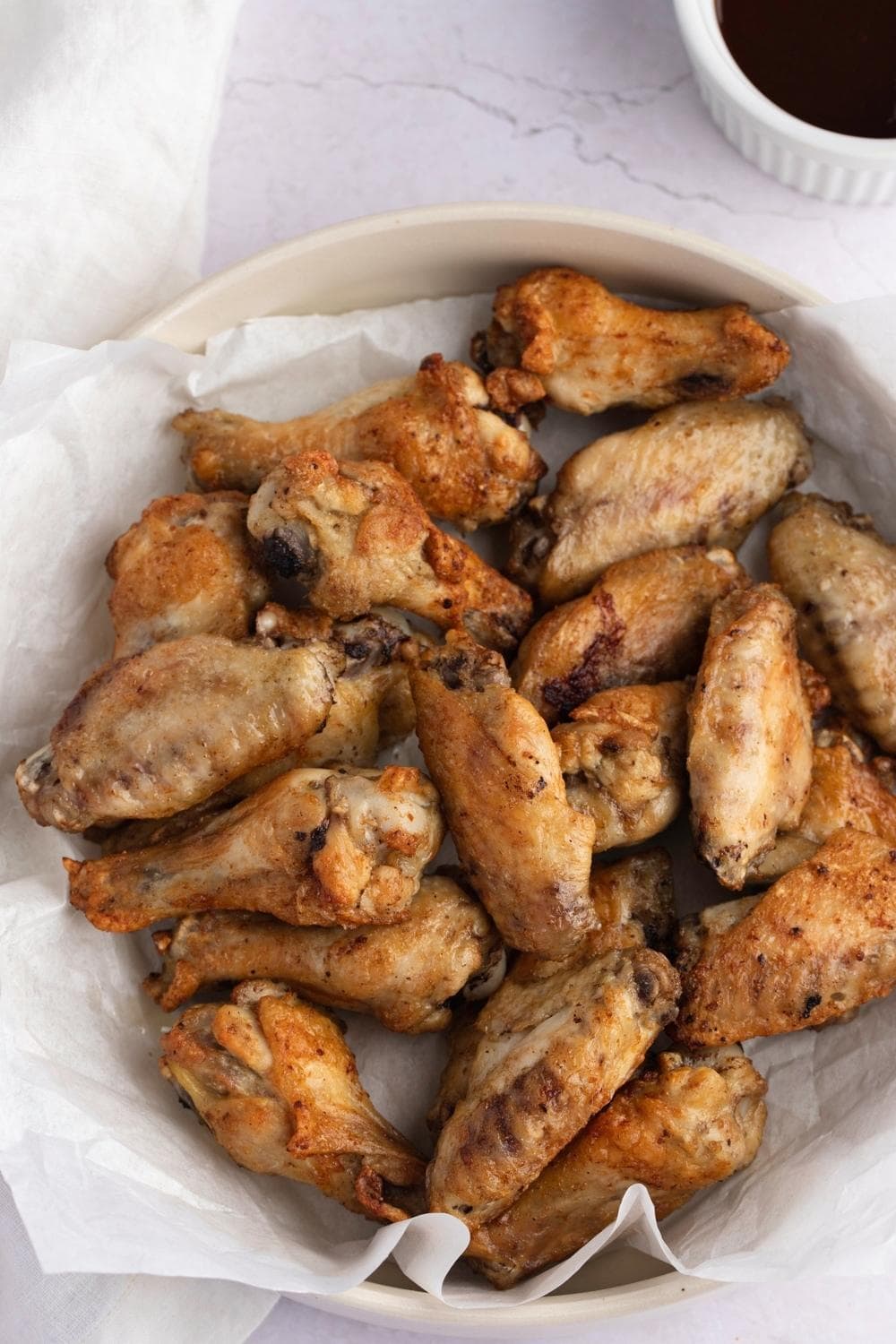 Chicken wings in a bowl lined with parchment paper. 