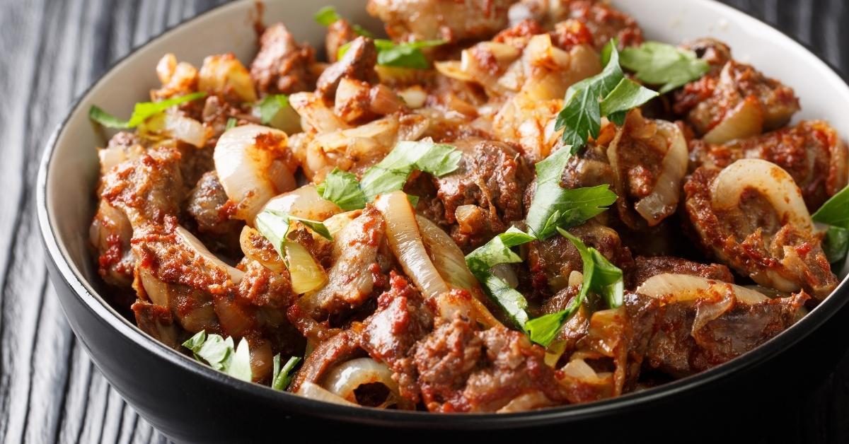 Fried Chicken Liver, Heart and Stomach with Onions, Tomatoes and Spices in a Black Bowl