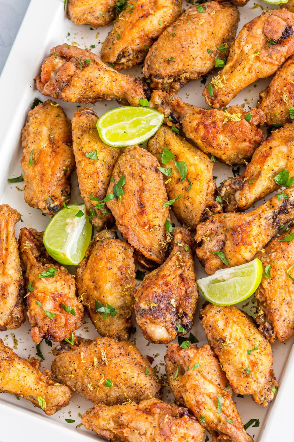 Chicken wings in a baking dish seasoned and garnished with lemon and herbs. 