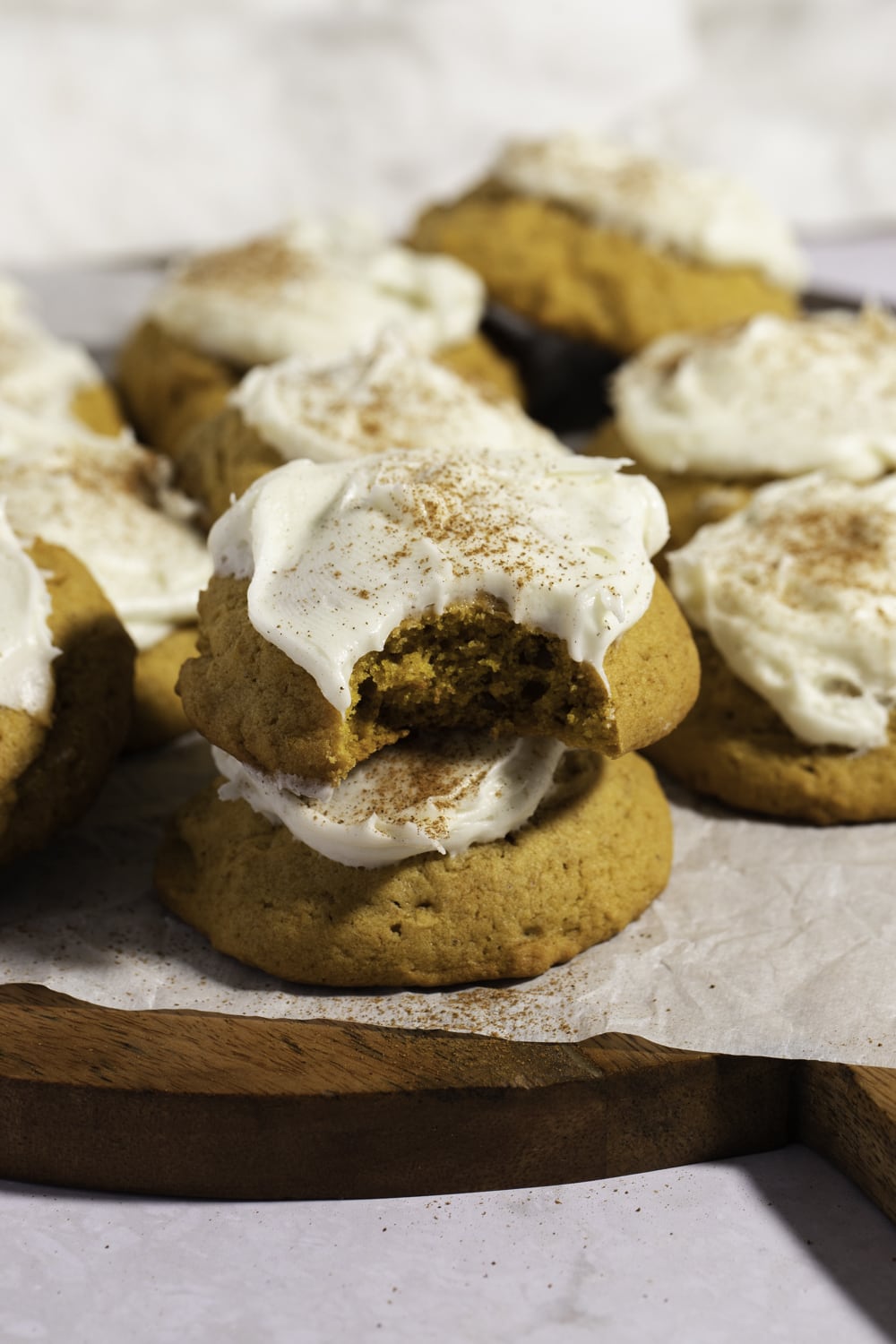 Pumpkin Cookies with Cream Cheese Frosting arranged on a wooden board.