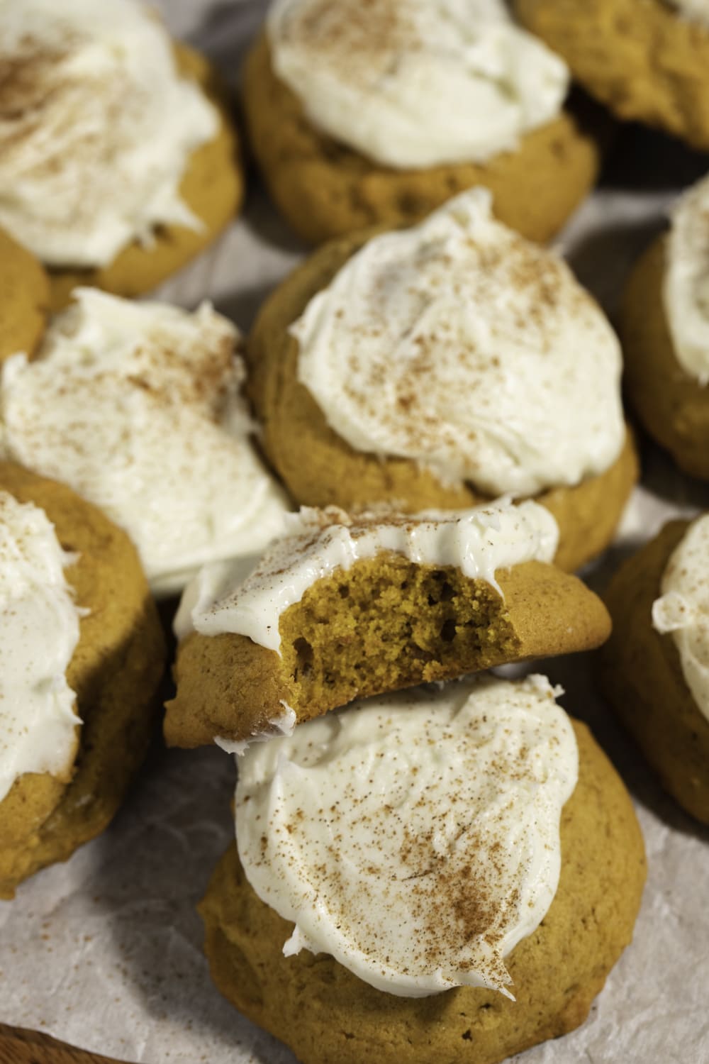 Pumpkin cookies with cream cheese frosting with cinnamon powder on top.