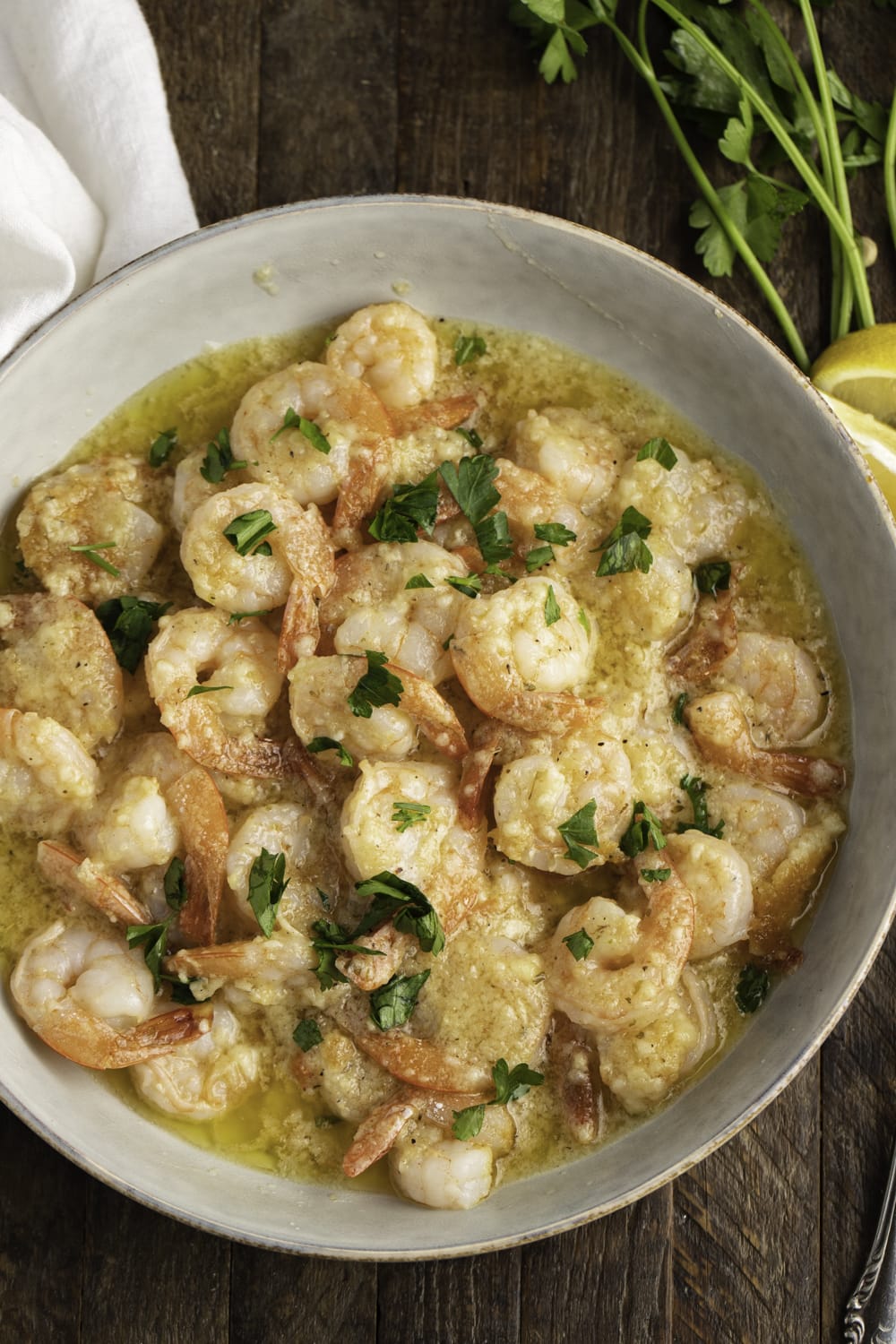 Bunch of shrimp with lemon and garlic butter sauce served on a bowl and garnished with chopped parsley