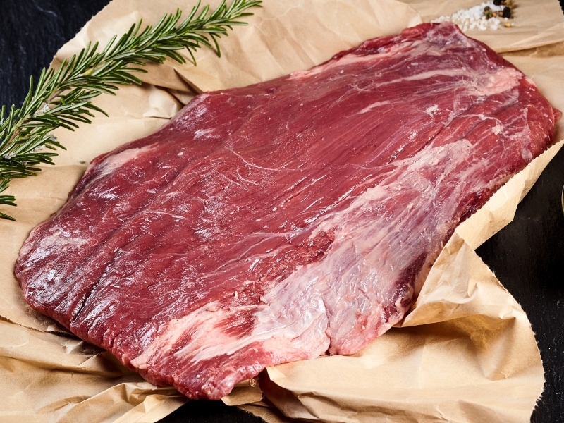 Raw Flank Steak on Top of Brown Bag with Fresh Rosemary