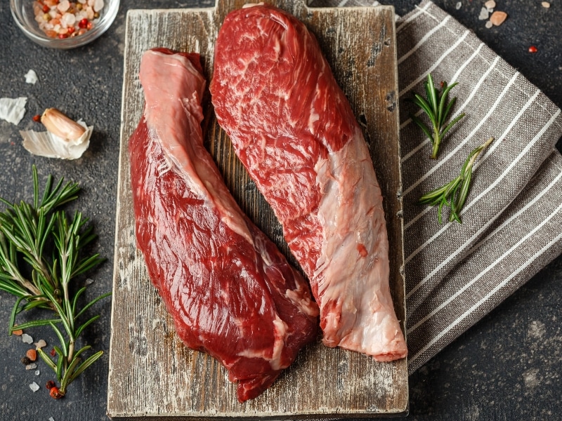 Raw Flap Steak on a Wooden Cutting Board with Rosemary and Seasoning