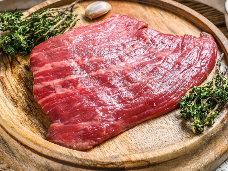 Raw Flat Iron Steak on a Round Cutting Board