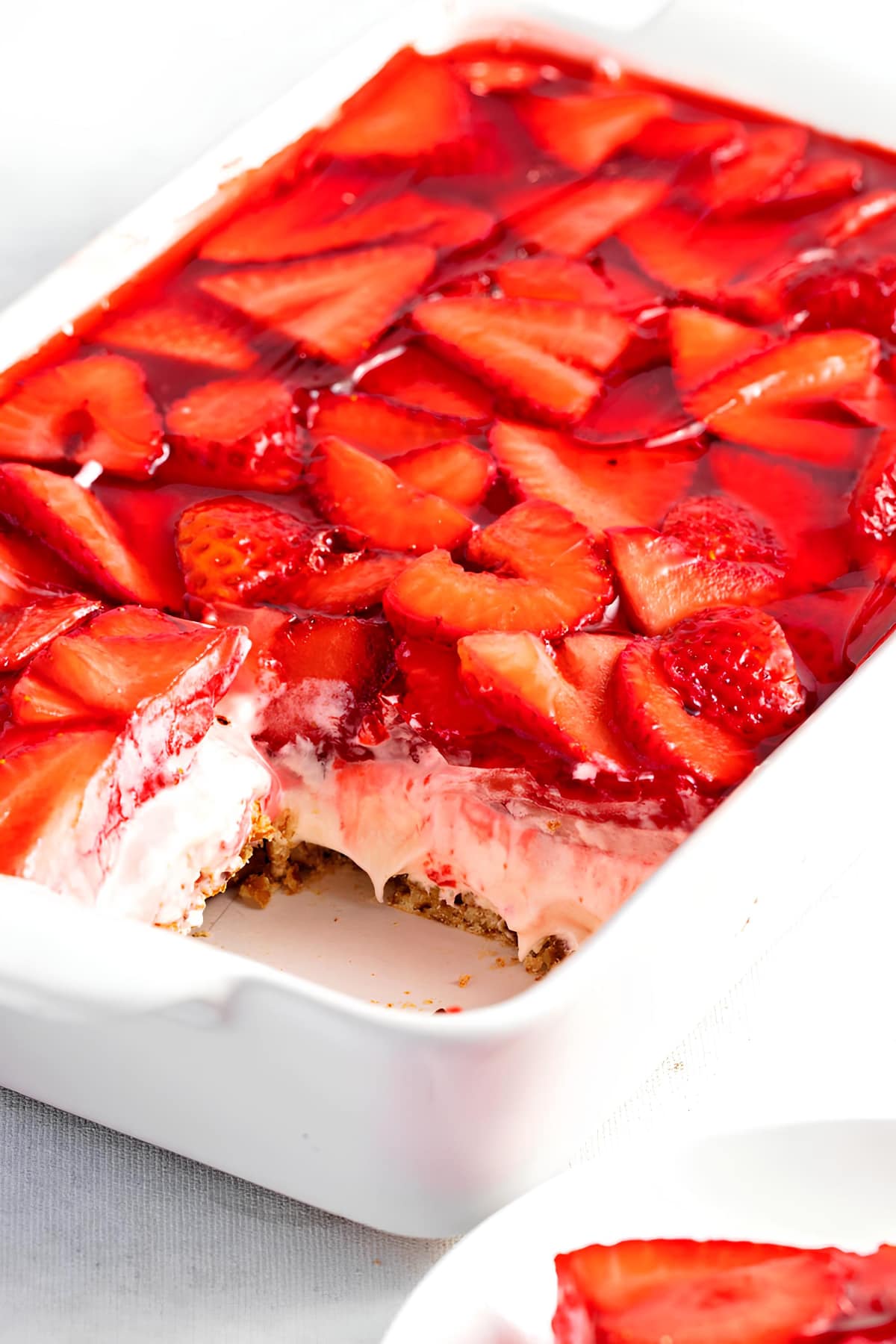 Layers of pretzels, cream cheese, and strawberry gelatin on a casserole 