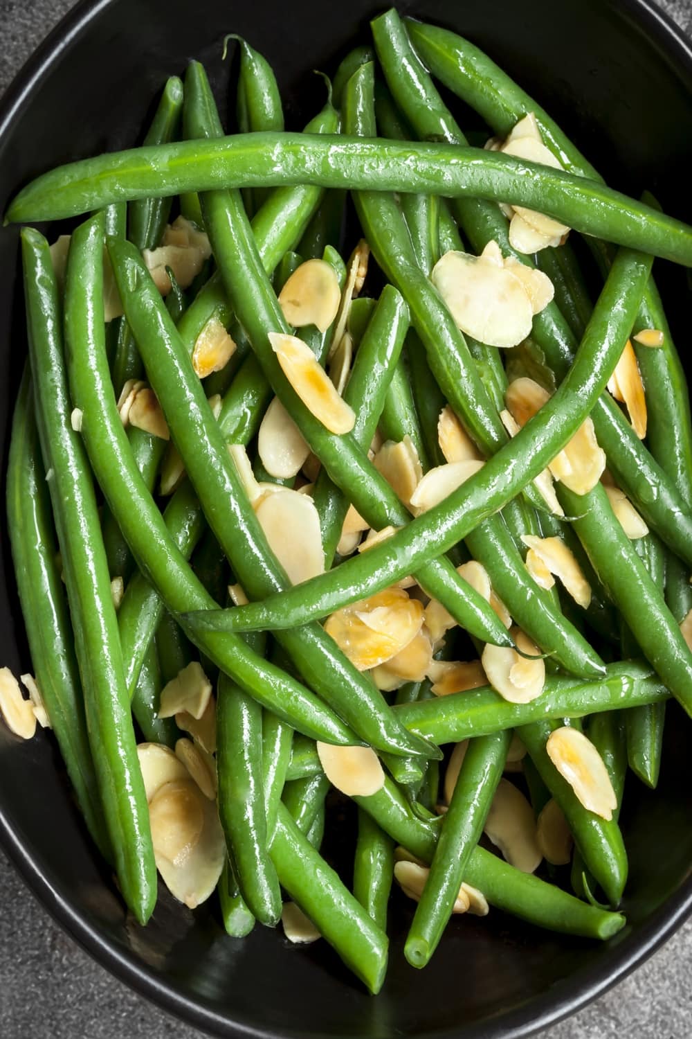 Green beans in a bowl with sliced almond nuts.