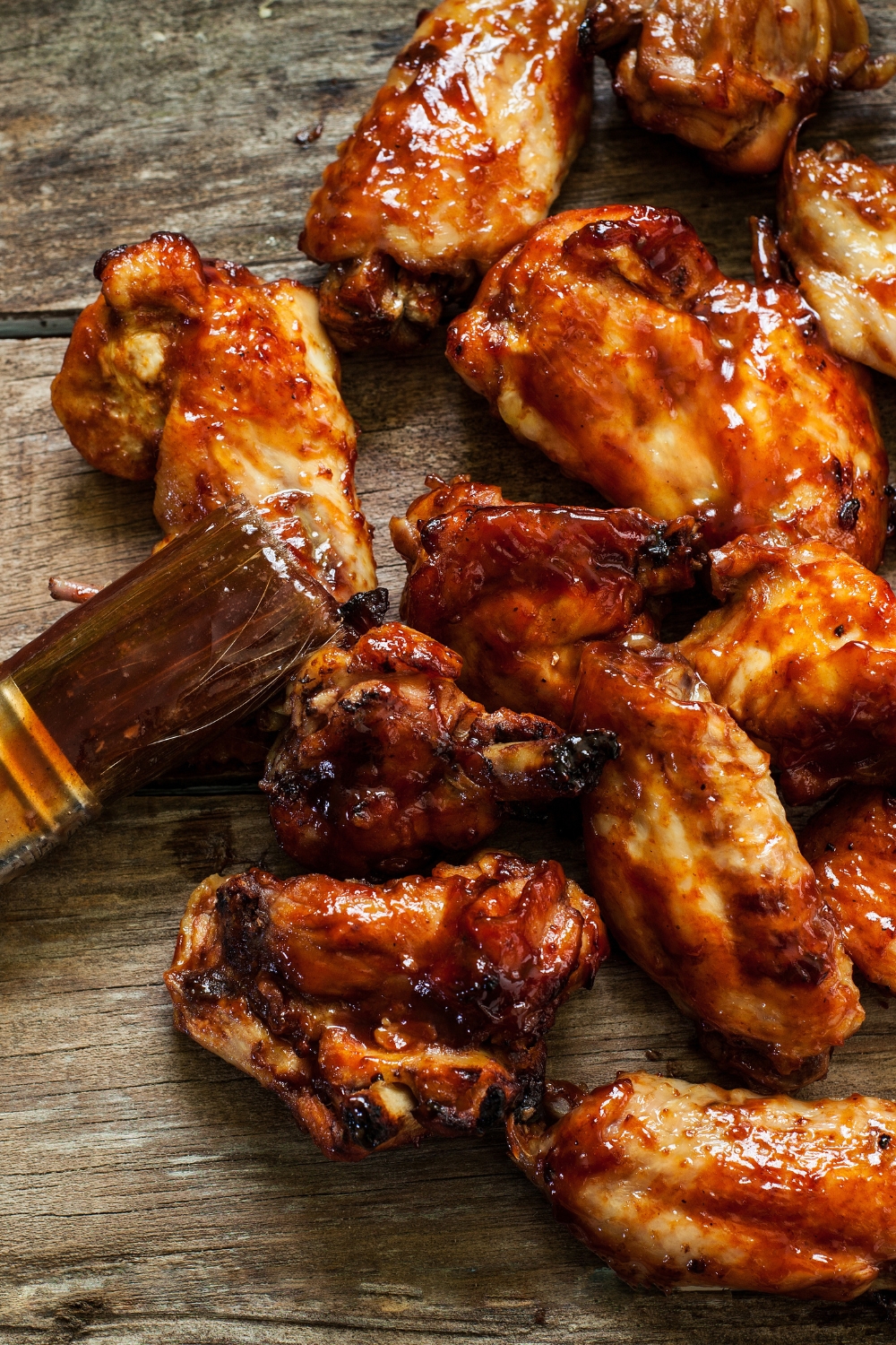 Chicken wings on a wooden board brushed with sauce. 