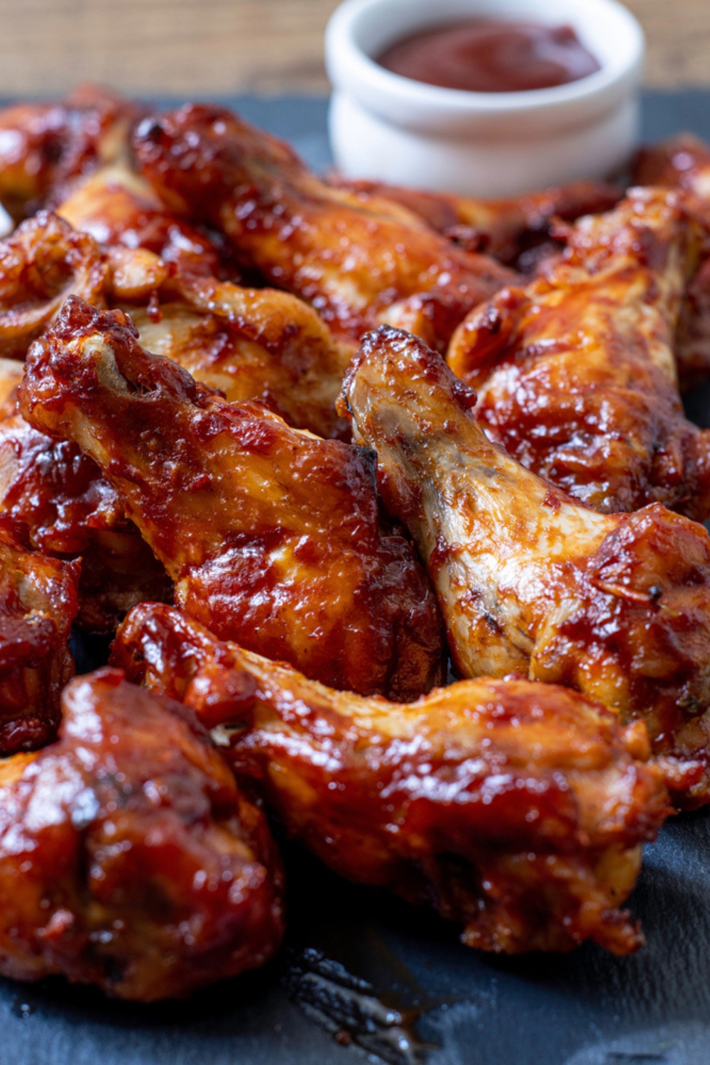 Chicken wings coated with marinade sauce served on a wooden tray. 