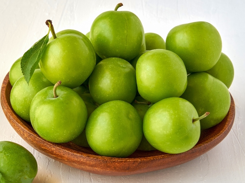 Sour Green Plums on a Wooden Bowl