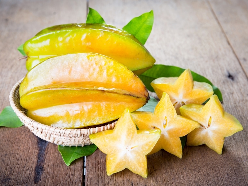Ripe Sliced and Whole Starfruit on Wooden Table