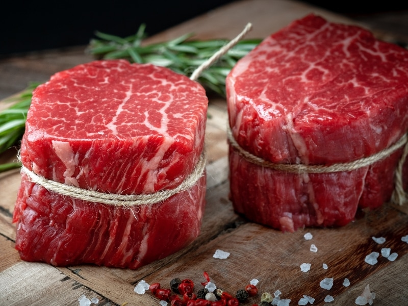 Raw Tenderloin Steak (Filet Mignon) on a Wooden Cutting Board with Salt and Pepper