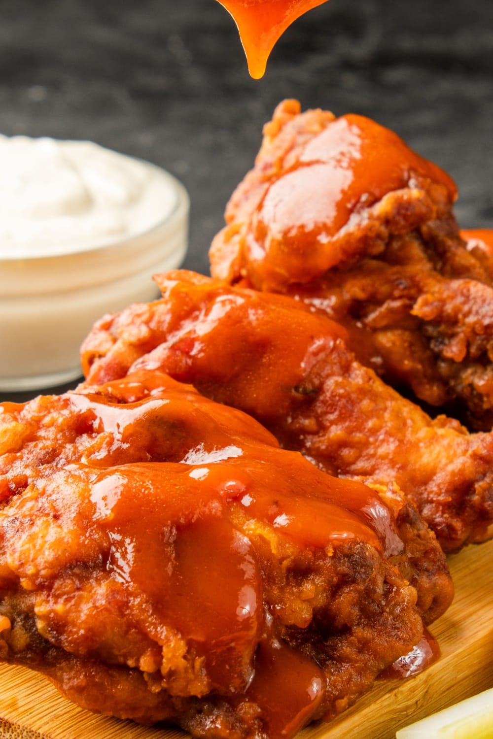 Close up of saucy buffalo chicken wings on a chopping board